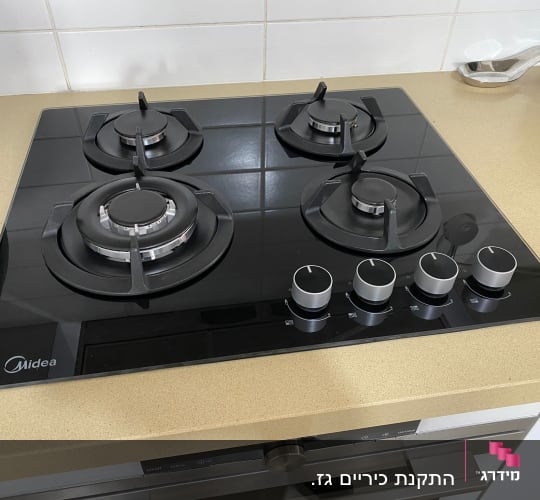 כיריים גז שחורות עם ארבעה מבערים וכפתורי שליטה